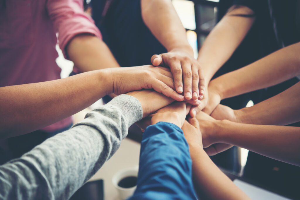 A group of hands overlapping together in the middle of a circle.